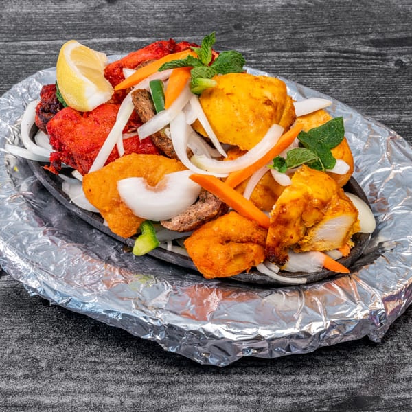Masala Indian Cuisine's sizzling platter with colorful chicken, onions, carrots, and a lemon wedge.