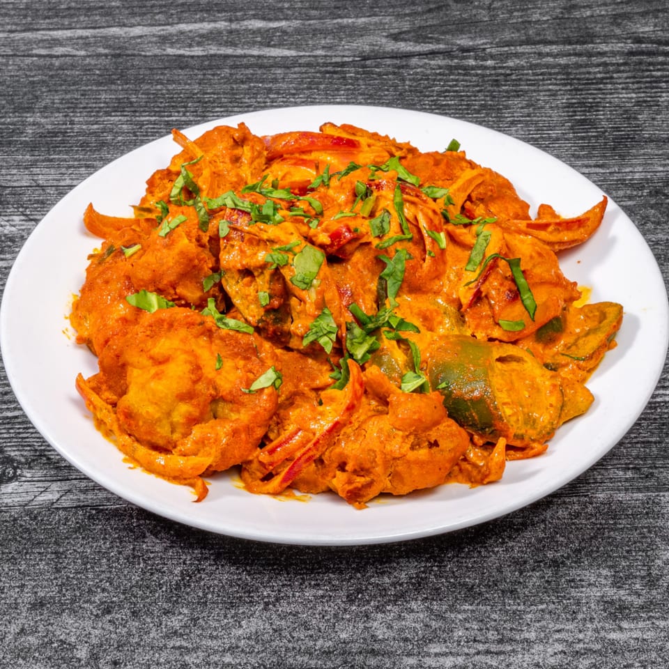Masala Indian Cuisine's vibrant orange chicken dish with green peppers and fresh herbs on a white plate.